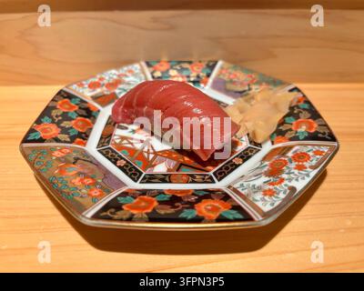 Sushi nigiri con tonno chutoro a contenuto medio di grassi, servito su un piatto tradizionale in ceramica colorata di Arita su un bancone di legno in un ristorante. Foto Stock
