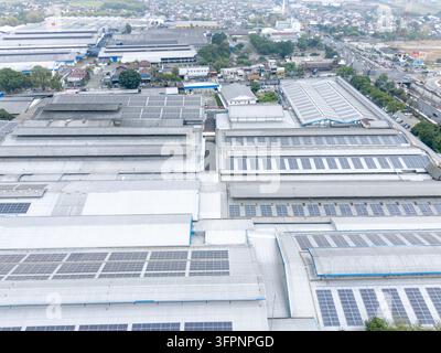 Vista aerea di un impianto industriale con estese installazioni di pannelli solari sui tetti della fabbrica in Indonesia. Foto Stock