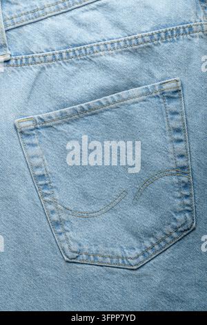 La tasca posteriore di jeans blu chiaro in primo piano mostra cuciture pulite e la trama del tessuto per il design dell'abbigliamento e le prove di moda Foto Stock