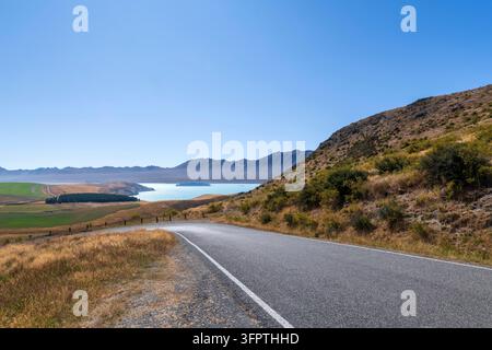 Sfondo stradale, piastra posteriore automobilistica, curva a gomito lastricata in un paesaggio rurale aspirazionale con vedute estese Foto Stock