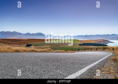 Sfondo stradale, piastra posteriore automobilistica, curva a gomito lastricata in un paesaggio rurale aspirazionale con vedute estese Foto Stock