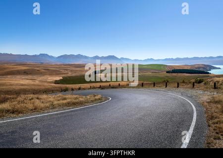 Sfondo stradale, piastra posteriore automobilistica, curva a gomito lastricata in un paesaggio rurale aspirazionale con vedute estese Foto Stock