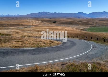 Sfondo stradale, piastra posteriore automobilistica, curva a gomito lastricata in un paesaggio rurale aspirazionale con vedute estese Foto Stock