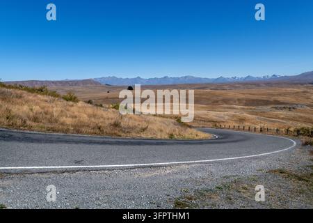 Sfondo stradale, piastra posteriore automobilistica, curva a gomito lastricata in un paesaggio rurale aspirazionale con vedute estese Foto Stock