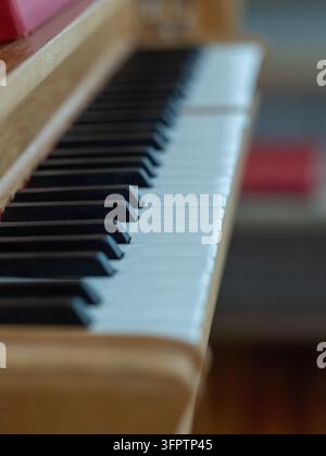 Primo piano dei tasti bianchi e neri di un pianoforte all'interno della chiesa di Puottaure nel nord della Svezia, fotografato con poca profondità di campo. Foto Stock