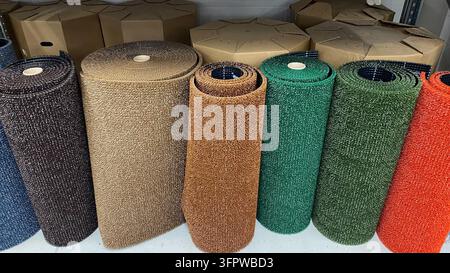 Rotoli colorati di erba artificiale e tappeto sintetico in diversi colori esposti in vendita in un negozio di bricolage Foto Stock