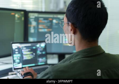 Sviluppatore maschile che scrive codice su più monitor Foto Stock