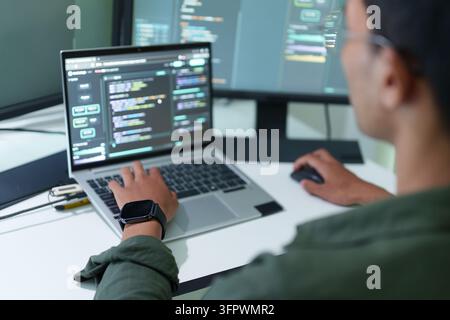 Vista sopra la spalla di uno sviluppatore che codifica su un laptop Foto Stock