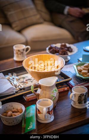 Tè, shortbread, brownies e patatine su un tavolino nel soggiorno di una casa di caccia a Glen Clova, Angus, Scozia Foto Stock