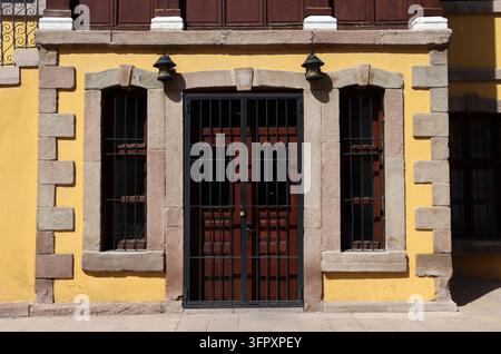 Una porta tradizionale e finestre in pietra di Sille a Konya. Le pareti della struttura del XX secolo sono dipinte di giallo. Foto Stock