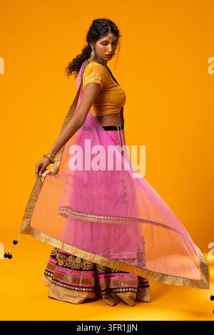 Donna afroamericana in lehenga ricamata che posa tenendo un dupatta trasparente in studio Foto Stock
