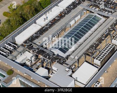 Grande edificio di data center con unità di raffreddamento industriali e tubi sul tetto piatto durante la giornata soleggiata per gestire le temperature dei server e fornire Foto Stock
