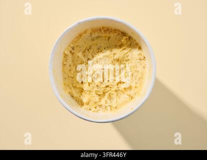 Contenitore di gelato aperto al gusto di frutta della passione e mango su sfondo giallo brillante, vista dall'alto Foto Stock