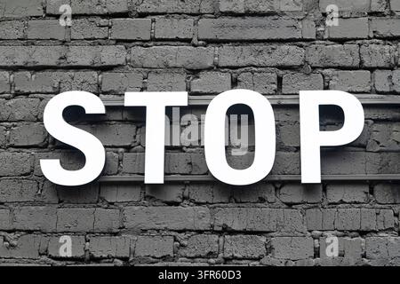 Indicazione del segnale di stop su un muro di pietra in mattoni grigi Foto Stock
