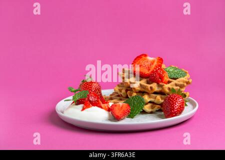 Gofrette belgiche con fragole e salsa di panna, servite con menta fresca Foto Stock