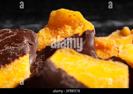 Mango immerso nel cioccolato su sfondo di legno nero Foto Stock