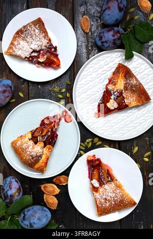Fette di torta aperta fatta in casa con prugne e cardamomo (galetta) e prugne blu scuro su sfondo scuro. Vista dall'alto Foto Stock