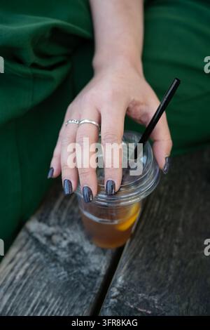 Donna che tiene una tazza di plastica di tè freddo con una cannuccia Foto Stock