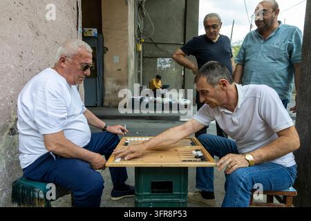 Uomini che giocano a backgammon su un tavolo di legno allestito in strada mentre altri osservano, Yerevan, Yerevan, Armenia Foto Stock