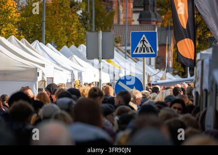 Folle di persone che camminano attraverso un affollato mercato all'aperto con tende bianche dei venditori in autunno Foto Stock