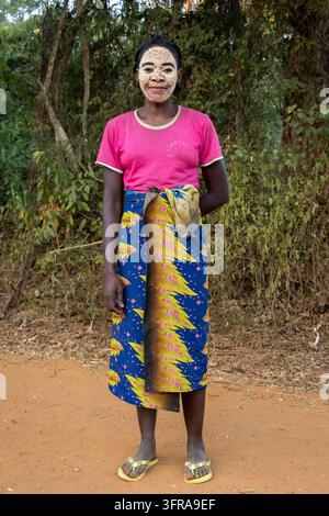 Ritratto a figura intera di una donna con una maschera tradizionale in argilla sul viso che indossa una gonna avvolgente stampata, Melaky, Bekopaka, Madagascar Foto Stock