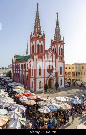 Vista elevata di una cattedrale a due torri che sovrasta un mercato di strada affollato al tramonto, Regione Marittima, Lomé, Togo Foto Stock