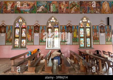 Interno di una chiesa con vetrate colorate e santi dipinti sopra pellegrini riposanti, Regione Marittima, Togoville, Togo Foto Stock