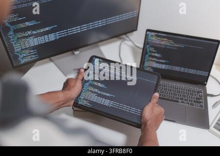 Sviluppatore di software che codifica su laptop e tablet in un moderno spazio di lavoro. Primo piano del flusso di programmazione, ingegneria del software, debugging del codice sorgente, a Foto Stock