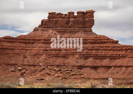 Vista ravvicinata di una formazione rocciosa rossa a strati sormontata da diverse colonne di pietra a cappuccio piatto nel deserto dello Utah, USA. Strati rocciosi orizzontali, detrito eroso Foto Stock