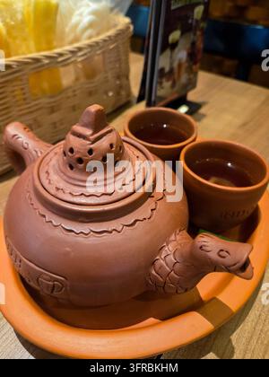 Riau, Indonesia - 11 ott. 2026: Autentico servizio da tè Teh Poci indonesiano realizzato in tradizionale ceramica di terracotta, servito caldo su tavolo di legno Foto Stock