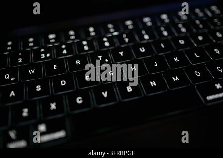 Primo piano di una tastiera di laptop retroilluminata con luce fioca e messa a fuoco poco profonda Foto Stock