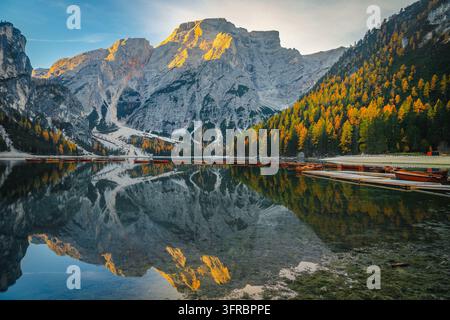 Un paesaggio mattutino sereno e mozzafiato con il Lago di Braies in Alto Adige. Riflessione straordinaria con vette alpine, larici colorati e fila di legno Foto Stock