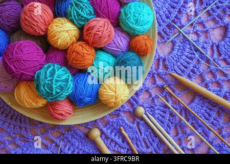 Palline di lana colorate, vari ferri da maglia e uncini per uncinetto Foto Stock