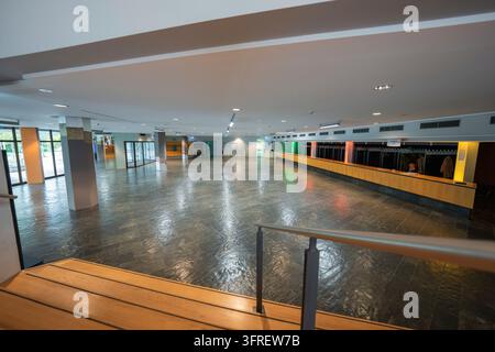 Un ampio atrio vuoto con pavimento lucido, bancone lungo e guardaroba, congresso di Halle Boeblingen, Germania Foto Stock