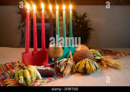 Kinara Kwanzaa che mostra candele mishumaa saba accese, con frutti e verdure simbolici del raccolto Foto Stock