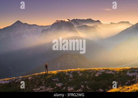 Escursionista in piedi su una cresta rocciosa al tramonto in autunno Foto Stock