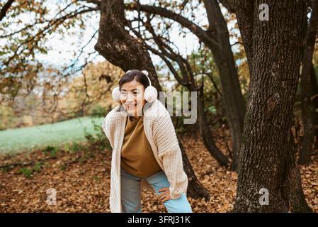 Donna anziana felice che si gode una passeggiata autunnale in una foresta tranquilla. Foto Stock
