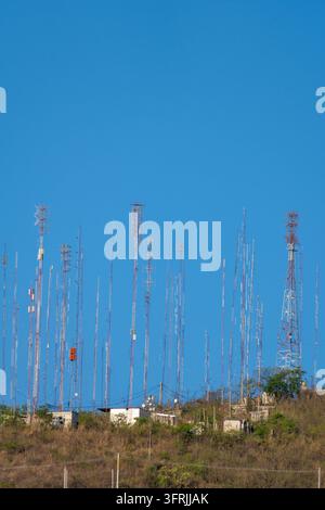 Molte antenne e torri di telefonia cellulare affollano una collina, creando un paesaggio di iperconnettività e infrastruttura di comunicazione moderna Foto Stock