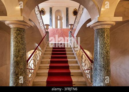 Scalinata imperiale con colonne di marmo verde, ringhiere in ferro battuto e medaglioni a ritratto all'interno del Palazzo Nicolaci a Noto, Sicilia Foto Stock