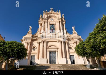 Facciata di chiesa barocca tardo con statue, orologio e ampia scalinata in pietra a Modica Alta, provincia di Ragusa, Italia, in una limpida mattina di dicembre Foto Stock