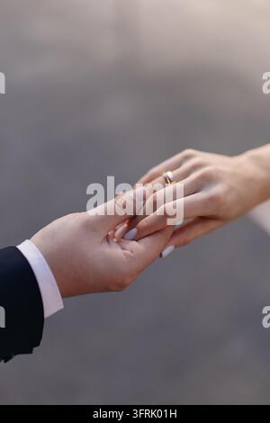 Primo piano dello sposo che tiene la mano della sposa mostrando gli anelli di fidanzamento. Momento romantico, coppia innamorata, matrimonio, partnership, impegno, cura, sostegno, te Foto Stock