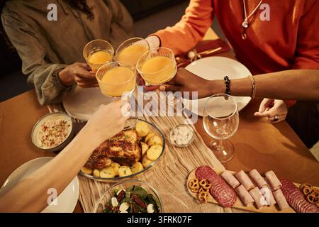 Amici multietnici che brindano con bevande durante una cena festosa Foto Stock