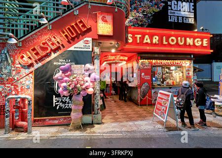 Insegna al neon rossa, scala ricoperta di graffiti e un chiosco di kebab fuori dai locali notturni nella capitale del Giappone, con un banco di fiori di congratulazioni. Foto Stock
