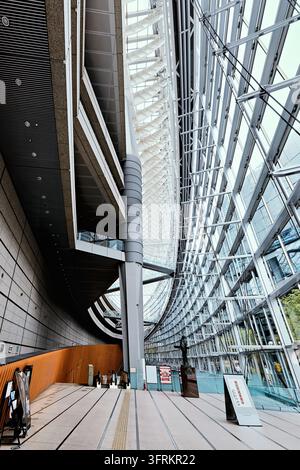 Tetto a traliccio d’acciaio curvo e pareti vetrate all’interno dell’edificio di vetro a Marunouchi, Chiyoda, Tokyo, progettato dall’architetto Rafael Vinoly. Foto Stock