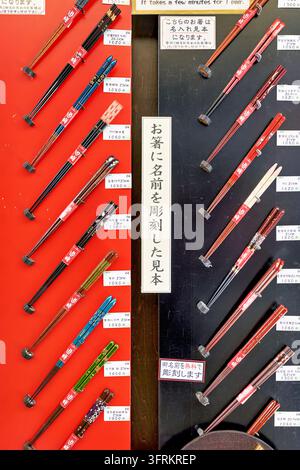Campioni di bacchette personalizzati con incisione del nome gratuita, prezzi in yen su pannelli di esposizione rossi e neri in un negozio di souvenir giapponese. Foto Stock