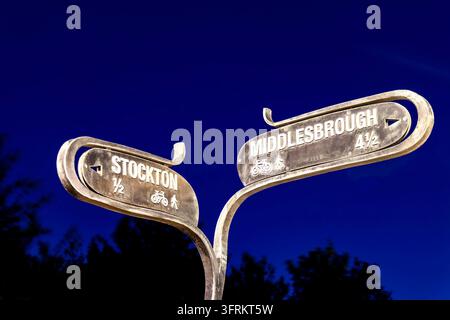 Segnale direzionale marrone che mostra Stockton e Middlesbrough su uno sfondo di cielo scuro di notte Foto Stock