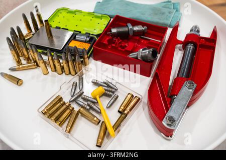 Vista ad angolo alto di un'attrezzatura per il ricaricamento dell'ammunizione domestica, dotata di bossoli in ottone, bilancia digitale e proiettili in piombo fuso per cartucce. Foto Stock