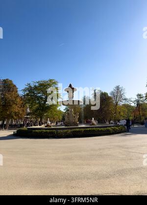 MADRID, SPAGNA - 09 OTTOBRE 2026 Fontana in pietra si trova in un parco di Madrid, circondata da alberi autunnali e visitatori che passeggiano. Gradini scolpiti monumentali a Foto Stock