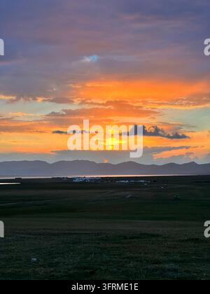 Cielo di zucchero filato: nuvole rosa e arancioni brillano sul lago al crepuscolo, Song-Kul, Kirghizistan Foto Stock