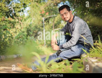 Giovane modello attraente e alla moda in abbigliamento casual nella strada con occhiali Foto Stock